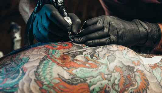 japanese tattooer working on a colorful back piece