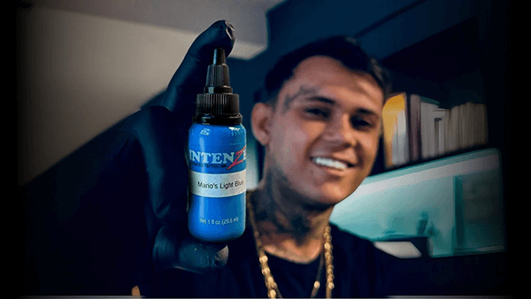 Person holding a bottle of Intenze tattoo ink with a blurred background