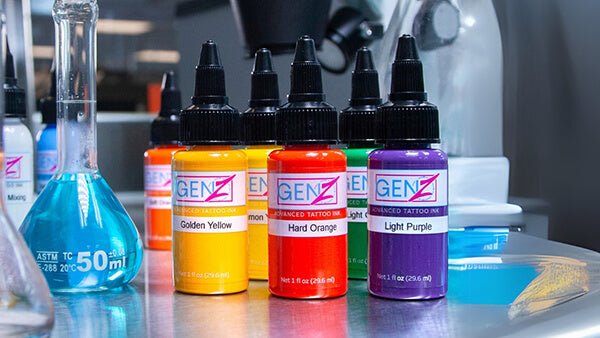 Bottles of GENZ tattoo ink in various colors on a reflective surface.
